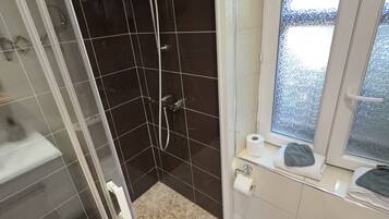 Un baño con ducha de vidrio, inodoro y ventana.