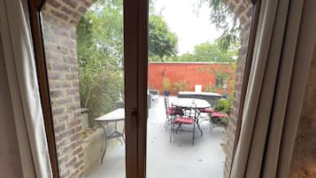 Una habitación con puerta corrediza de vidrio que da a un patio al aire libre con mesa y sillas.