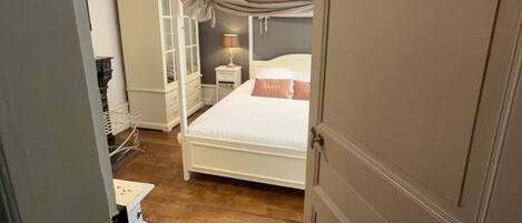 A bedroom with a bunk bed, a bedside table with a lamp, and a wardrobe.