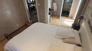 Un dormitorio con una cama grande, suelo de madera y vista a un baño por una puerta abierta.