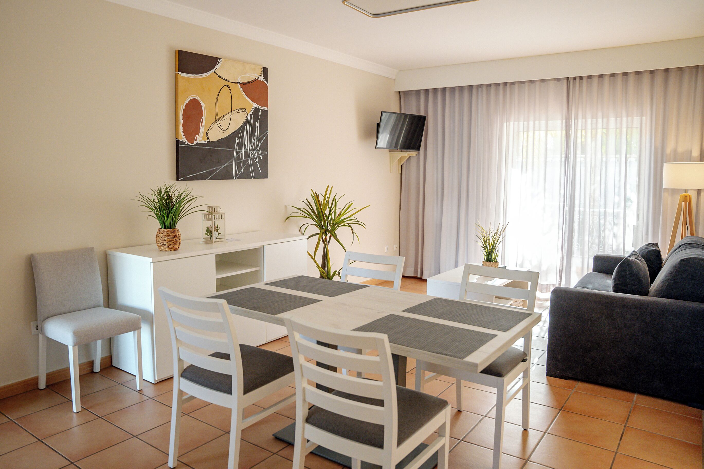 Un saló modern amb zona de menjador, que inclou una televisió de pantalla plana, un sofà i una taula de dinar amb cadires.
