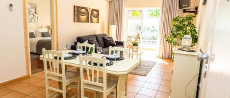 A dining area with a table set for four, a sofa, and a TV mounted on the wall.
