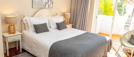 A neatly made bed with a grey blanket, two bedside lamps, and a large floral artwork on the wall.