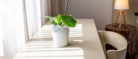 A room with a wooden table, a potted plant, a lamp, and a chair.