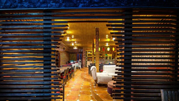 Un interior acogedor con listones de madera, suelo de baldosas y una zona de estar con mesas y sillas.