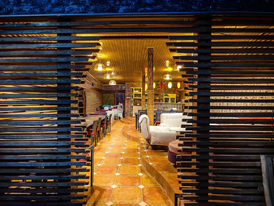 A cozy interior with wooden slats, a tiled floor, and a seating area with tables and chairs.