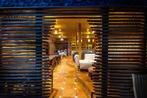 A cozy interior with wooden slats, a tiled floor, and a seating area with tables and chairs. - Space Hotel Apartments & Spa (Kampala)