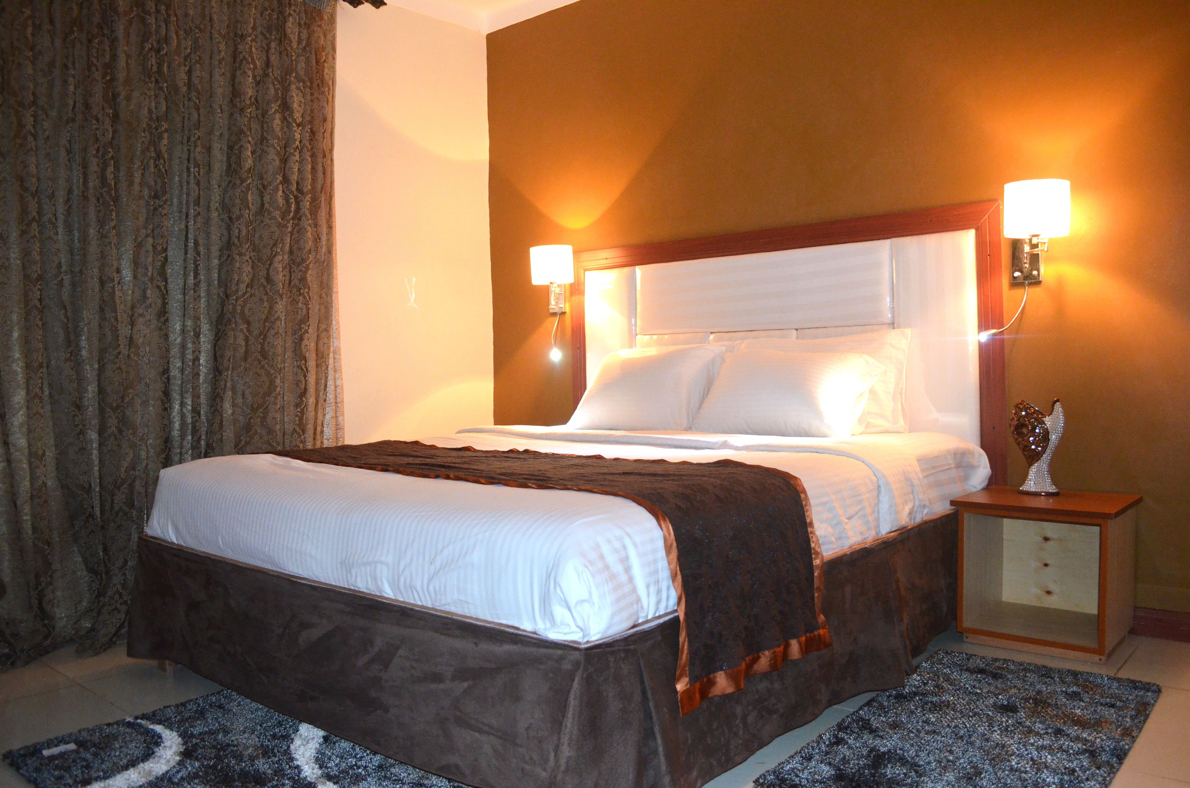 A hotel room with a large bed, two bedside lamps, a nightstand, and a decorative angel figure.