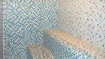 Un baño con paredes de mosaicos y un banco.