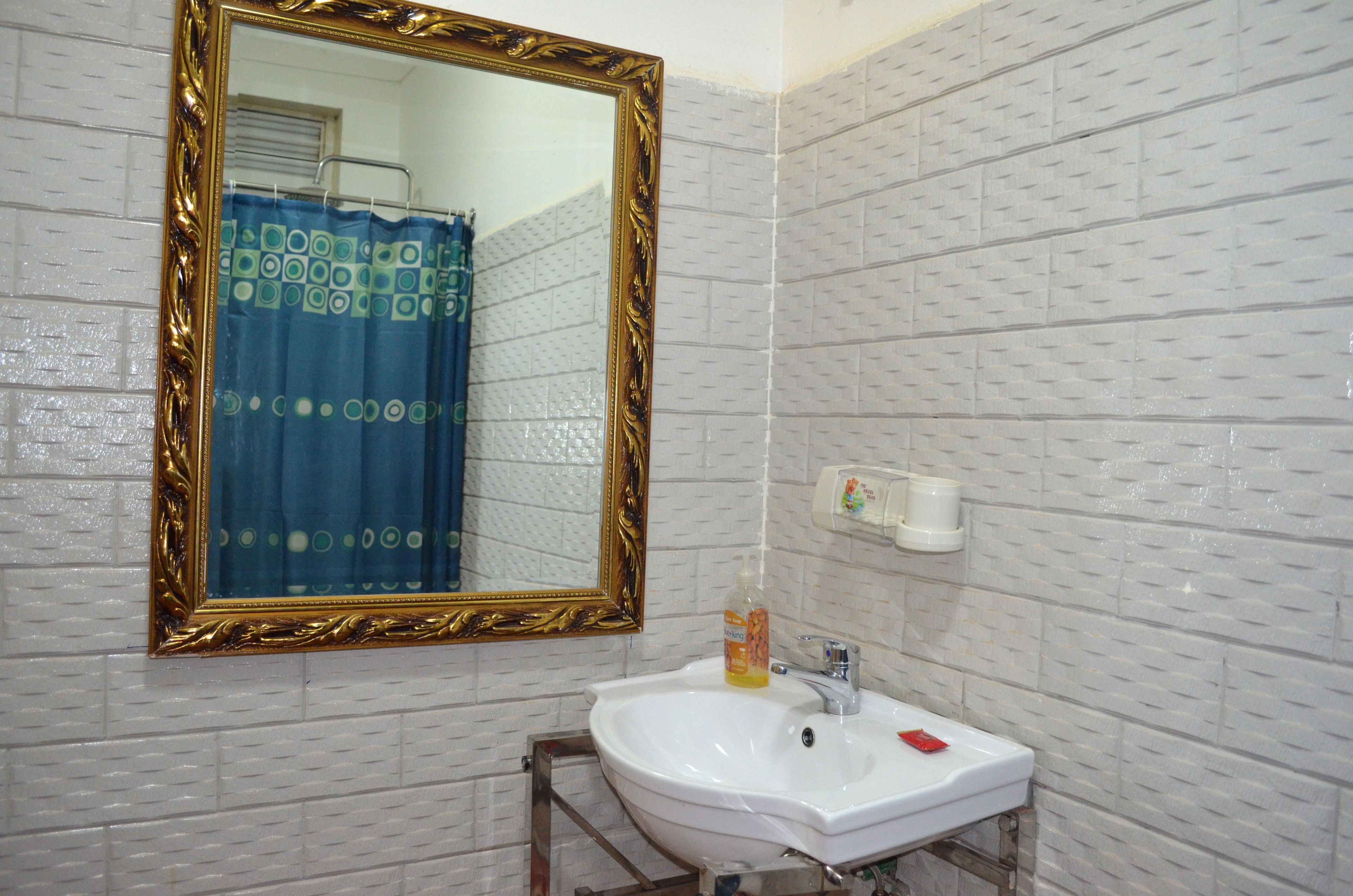 A bathroom with a white sink, a gold-framed mirror, and a blue shower curtain.