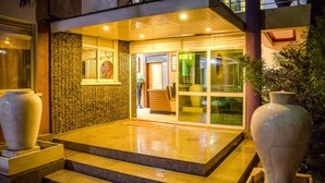 Entrada de un hotel con fachada de piedra, un jarrón grande y escalones que conducen a la puerta.