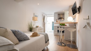Quarto moderno com uma cama grande, mesas de cabeceira, TV fixada na parede e vista para a área da cozinha.