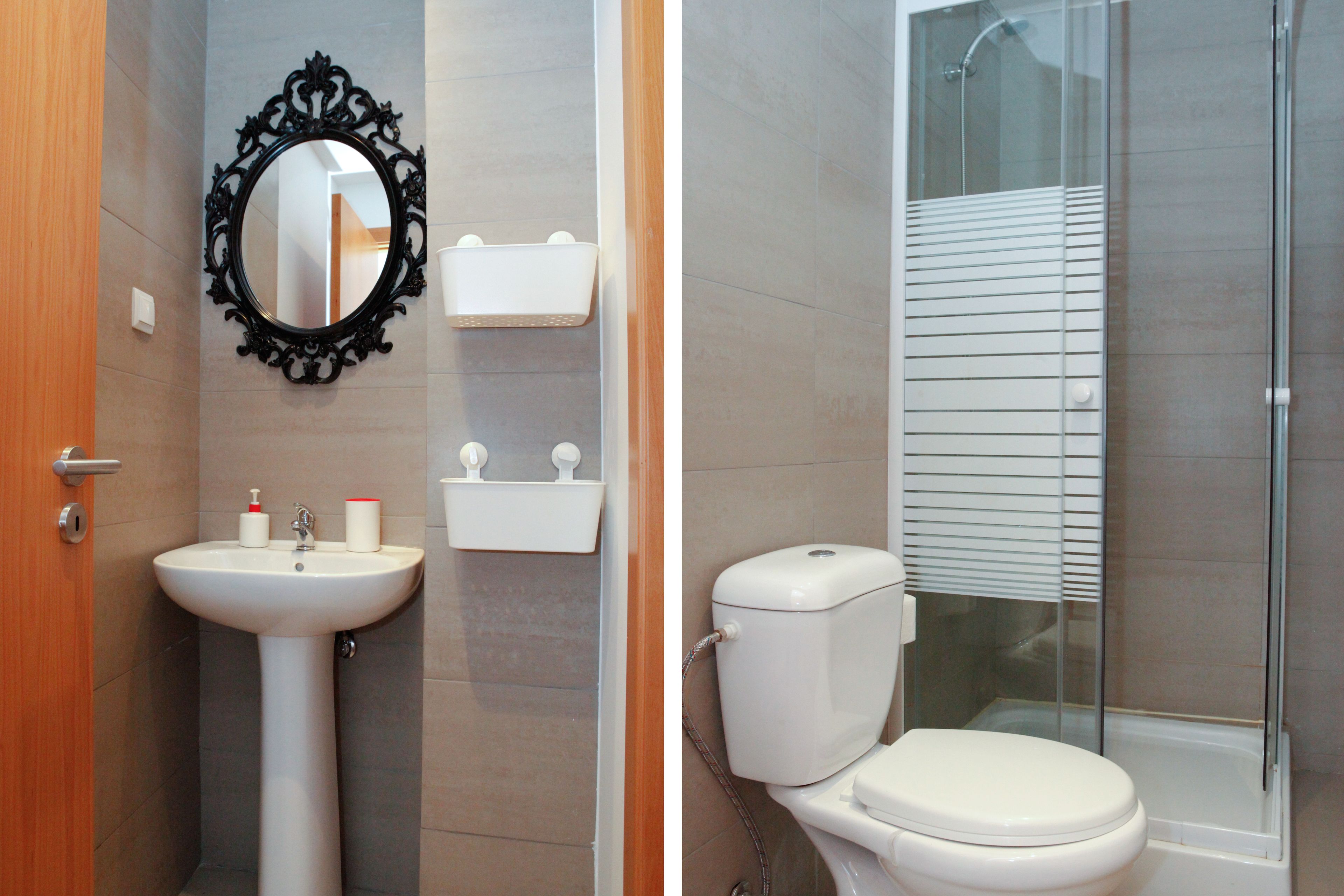Un baño con lavamanos pedestal, espejo en la pared, inodoro y cabina de ducha.