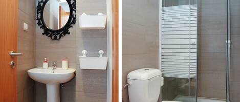 Un baño con lavamanos pedestal, espejo en la pared, inodoro y cabina de ducha.