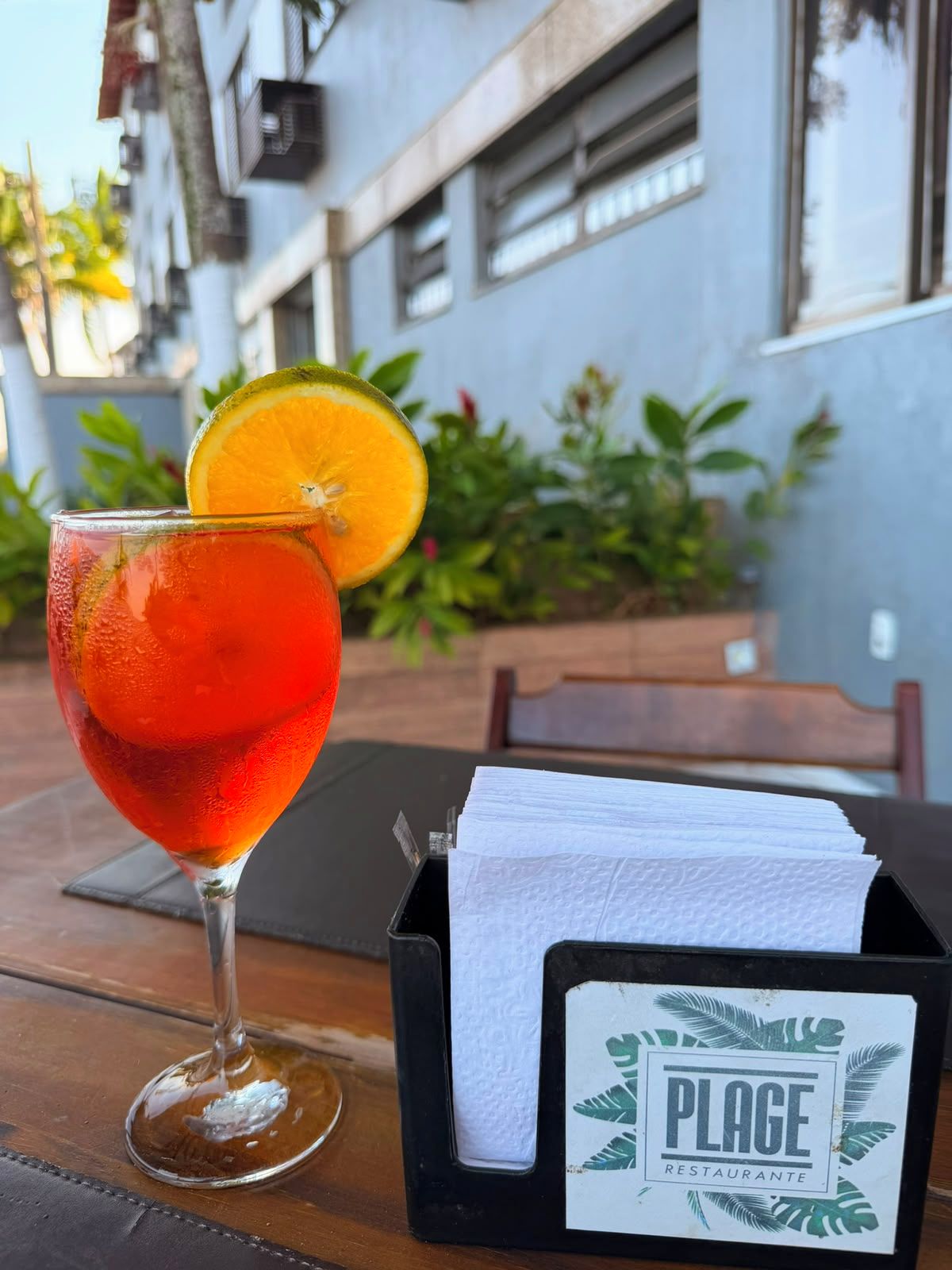Una mesa con una bebida, un porta servilletas y un cartel para Plage Restaurante.
