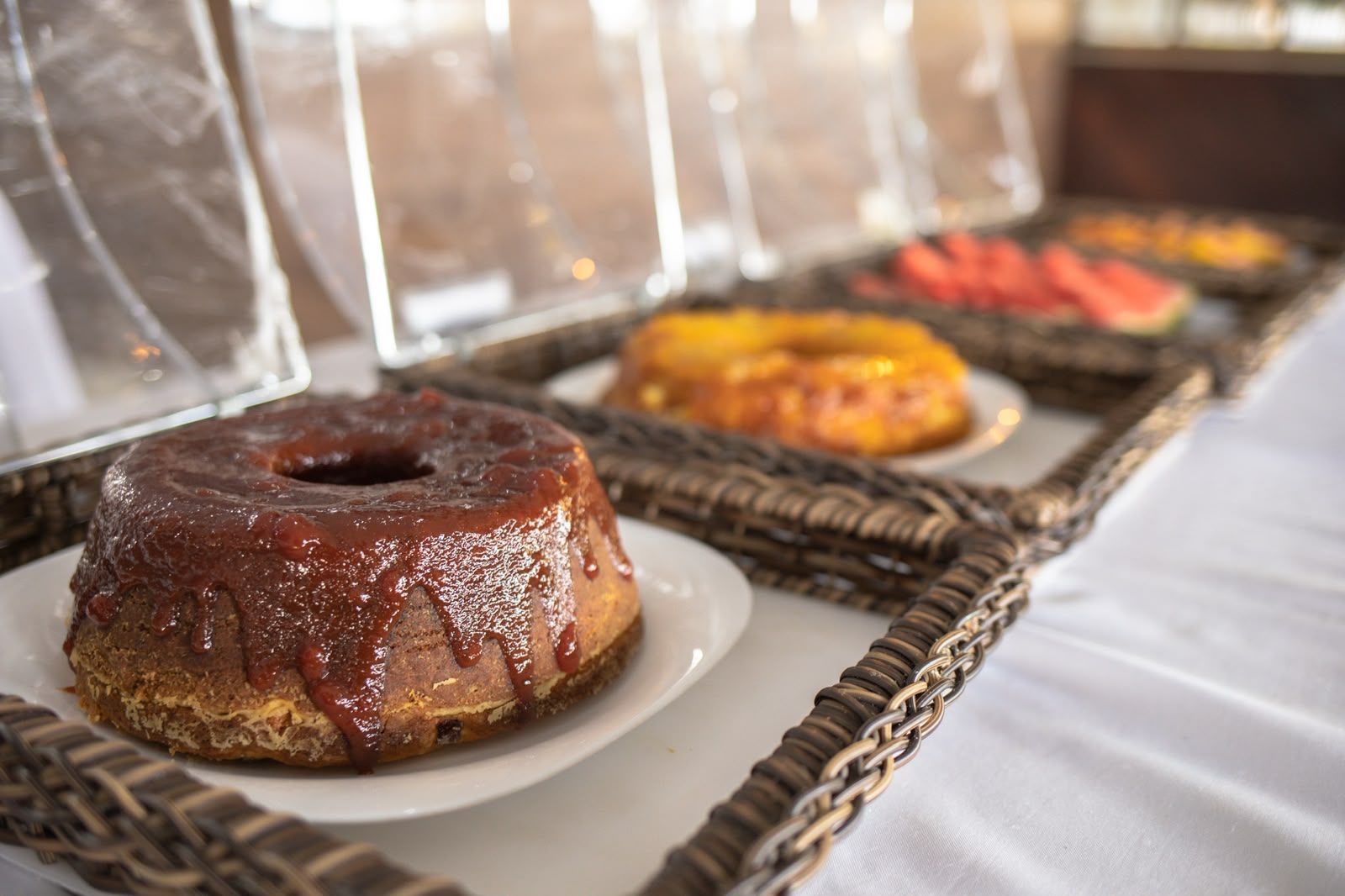 A buffet table with various food items, including a chocolate-glazed donut and a fruit platter.