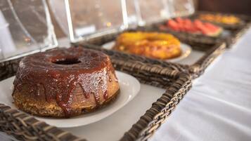 Una mesa de buffet con diferentes alimentos, incluyendo un donut glaseado de chocolate y una bandeja de frutas.