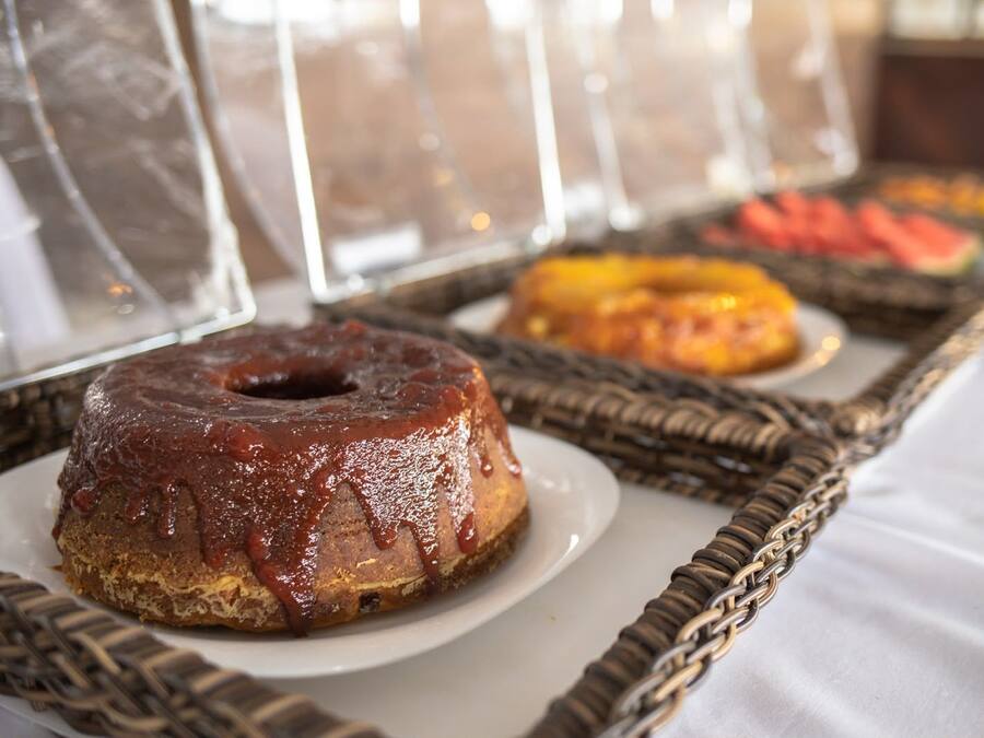 Una mesa de buffet con diferentes alimentos, incluyendo un donut glaseado de chocolate y una bandeja de frutas.