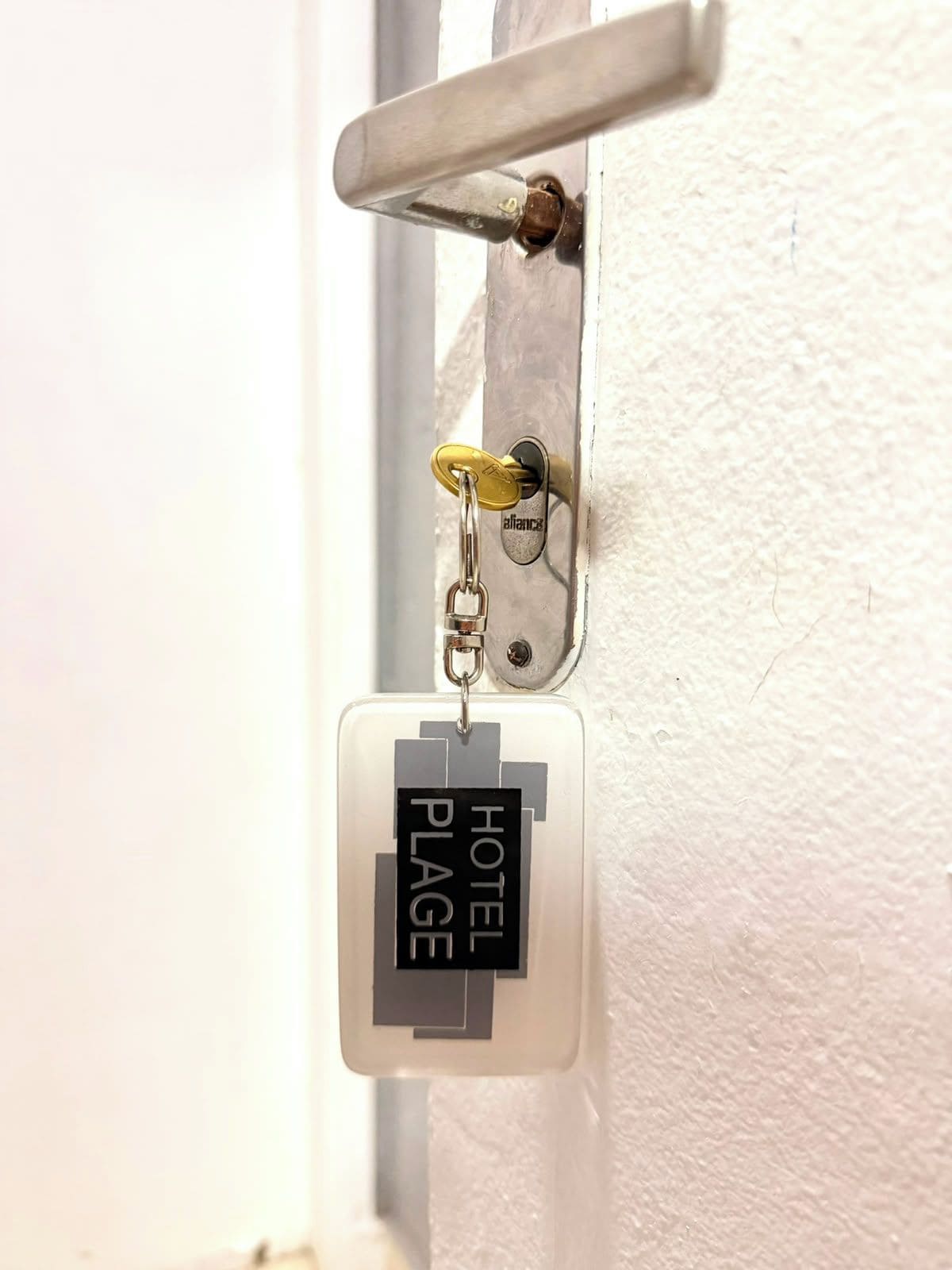 A hotel keycard with 'HOTEL PLAGE' text, attached to a door handle.