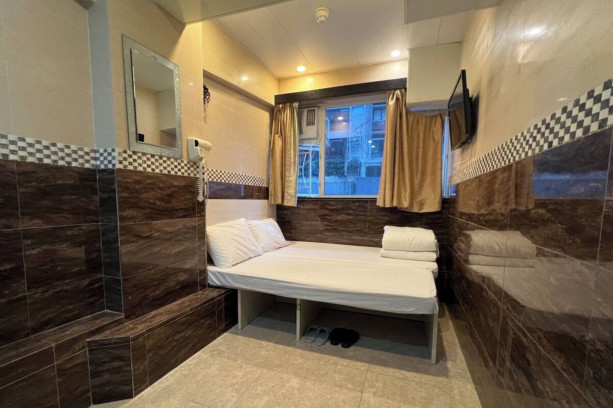 A modern bathroom with a bed, a mirror, and a window with curtains.
