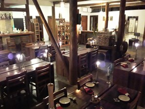 Ein Restaurant mit mehreren Tischen und Stühlen, einer Bar mit Flaschen und einem großen Spiegel, der das Innere widerzuspiegeln scheint.