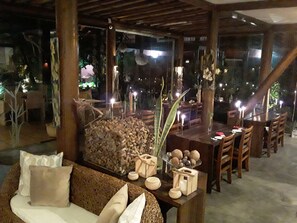 Un espace extérieur accueillant, aménagé avec une table et des chaises en bois, entouré de plantes et d’objets décoratifs.