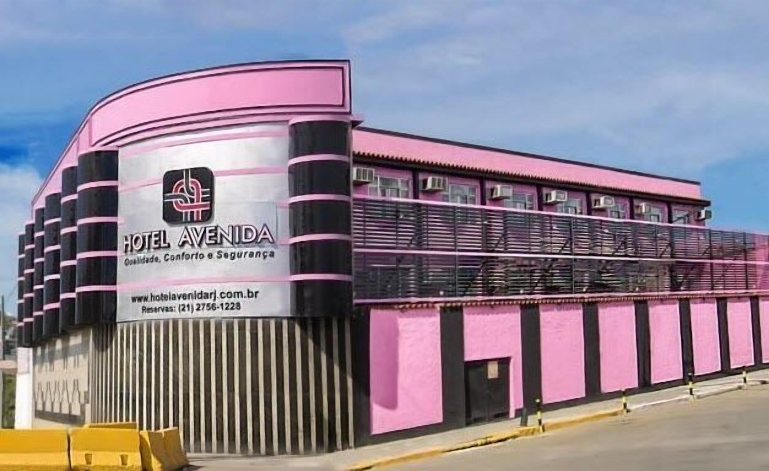 A pink building with a curved facade, a prominent logo, and contact information for HOTEL AVENIDA.