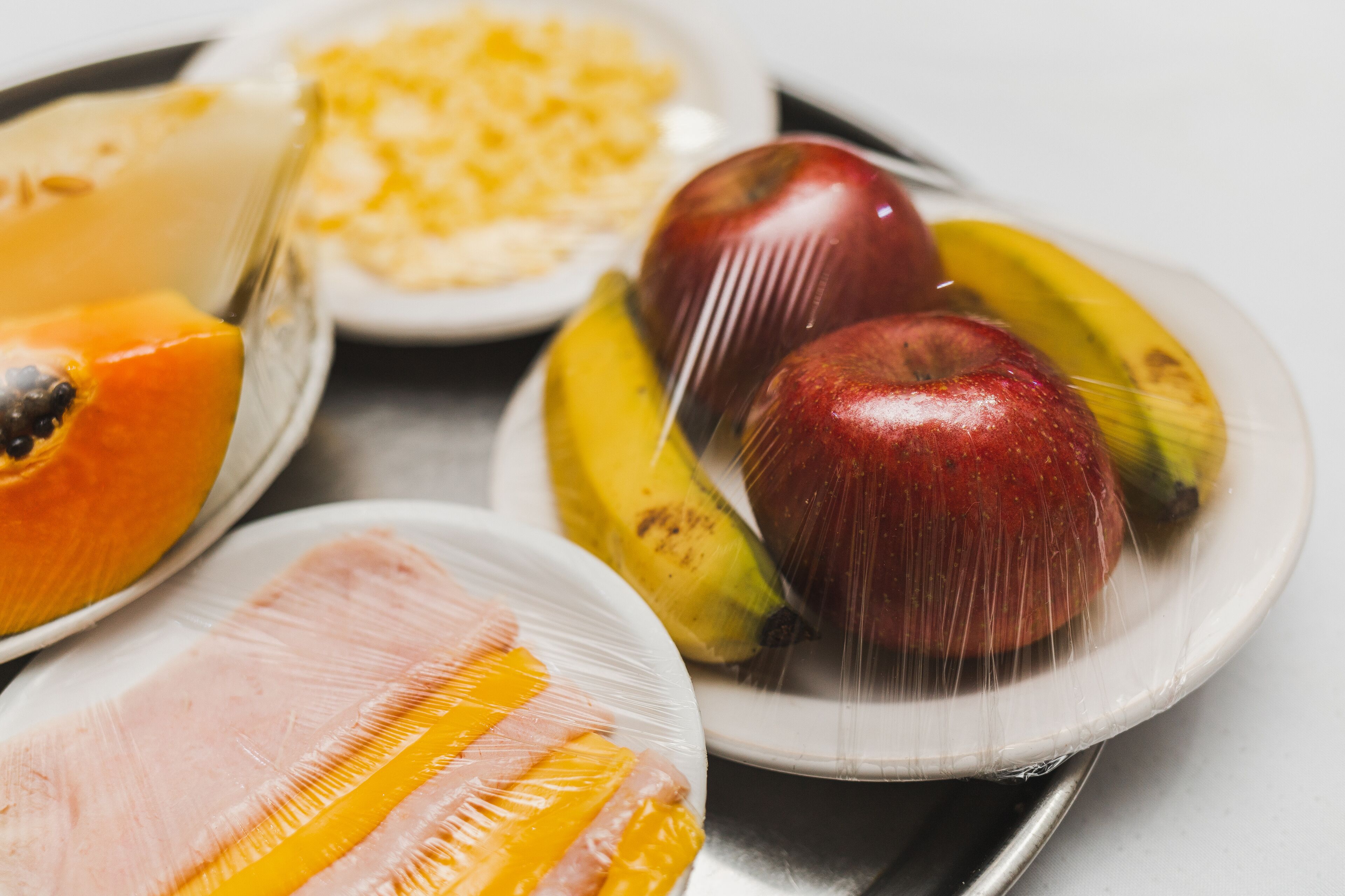 Una bandeja con diversos alimentos, incluyendo frutas y un jamón envuelto.