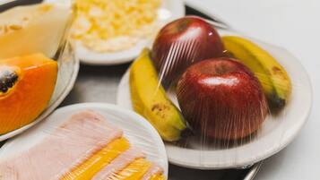 Una bandeja con diversos alimentos, incluyendo frutas y un jamón envuelto.