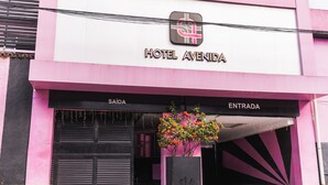 A hotel entrance with a sign reading "HOTEL AVENIDA" and two doors labeled "SAÍDA" and "ENTRADA". - Hotel Avenida (São João de Meriti)