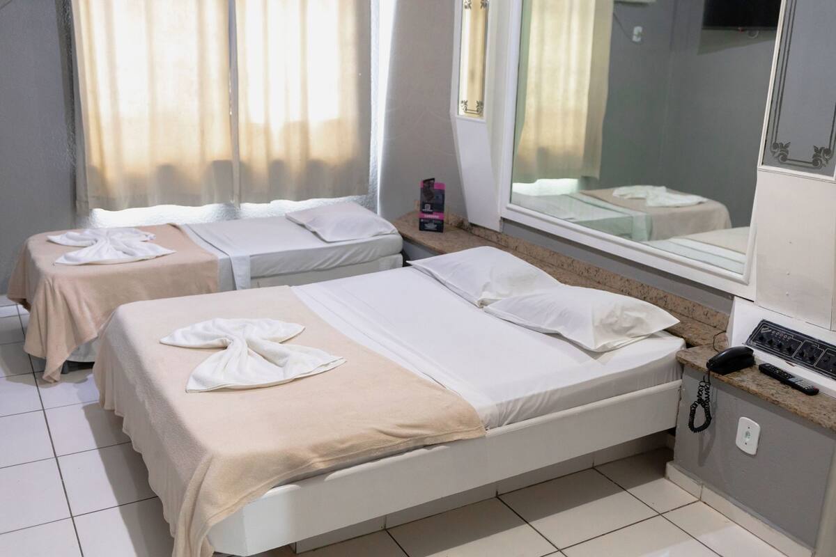 A hotel room with two beds, a bathroom, a telephone, and a mirror.