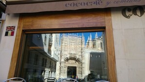 Fachada de un comercio con un amplio ventanal que refleja un edificio histórico.