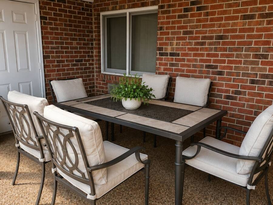 Un patio con una mesa y sillas, una planta en maceta y un muro de ladrillo.