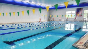 An indoor swimming pool with multiple lanes, safety ladders, and a lifeguard stand. - Alleghany Inn (Sparta)
