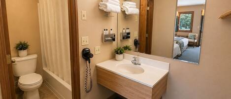 Ein Badezimmer mit Toilette, Waschbecken, Dusche, Spiegel und Telefon.
