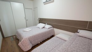 Un dormitorio con dos camas, un armario y un equipo de aire acondicionado.