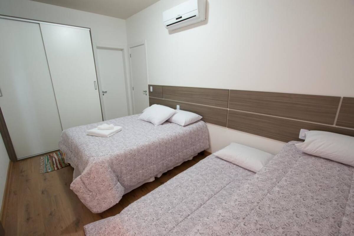 A bedroom with two beds, a wardrobe, and an air conditioning unit.