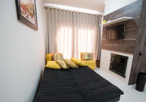 A bedroom with a bed, a fireplace, and a window with curtains. - Residencial Onze-1 (Gramado)