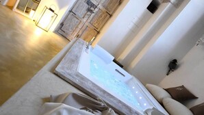 A room with a large bathtub, a wooden door, and a green bottle on the wall. - Palazzo Castriota (Alezio)