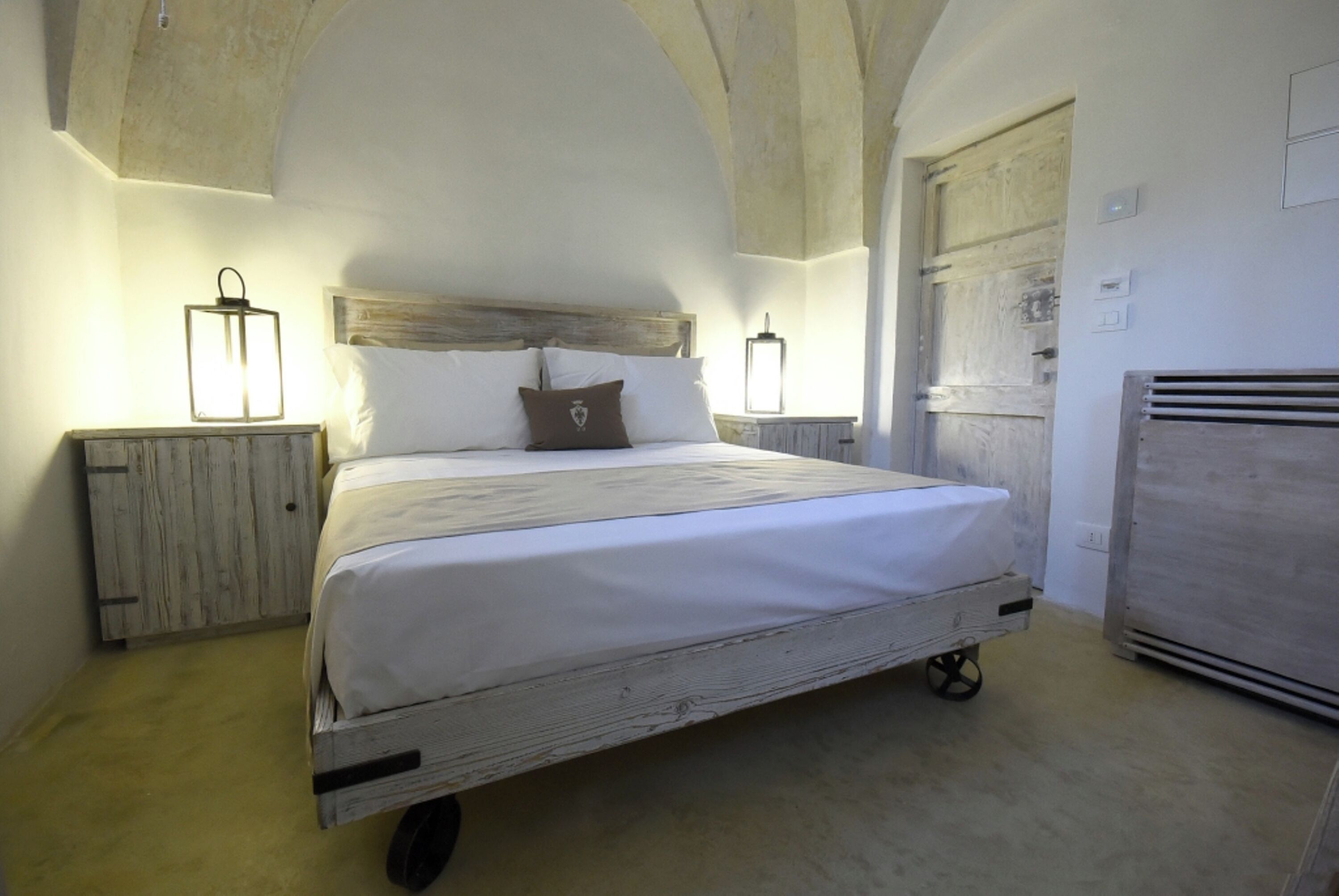 Une chambre à coucher avec un lit en bois, deux tables de chevet avec des lampes et un plafond rustique.
