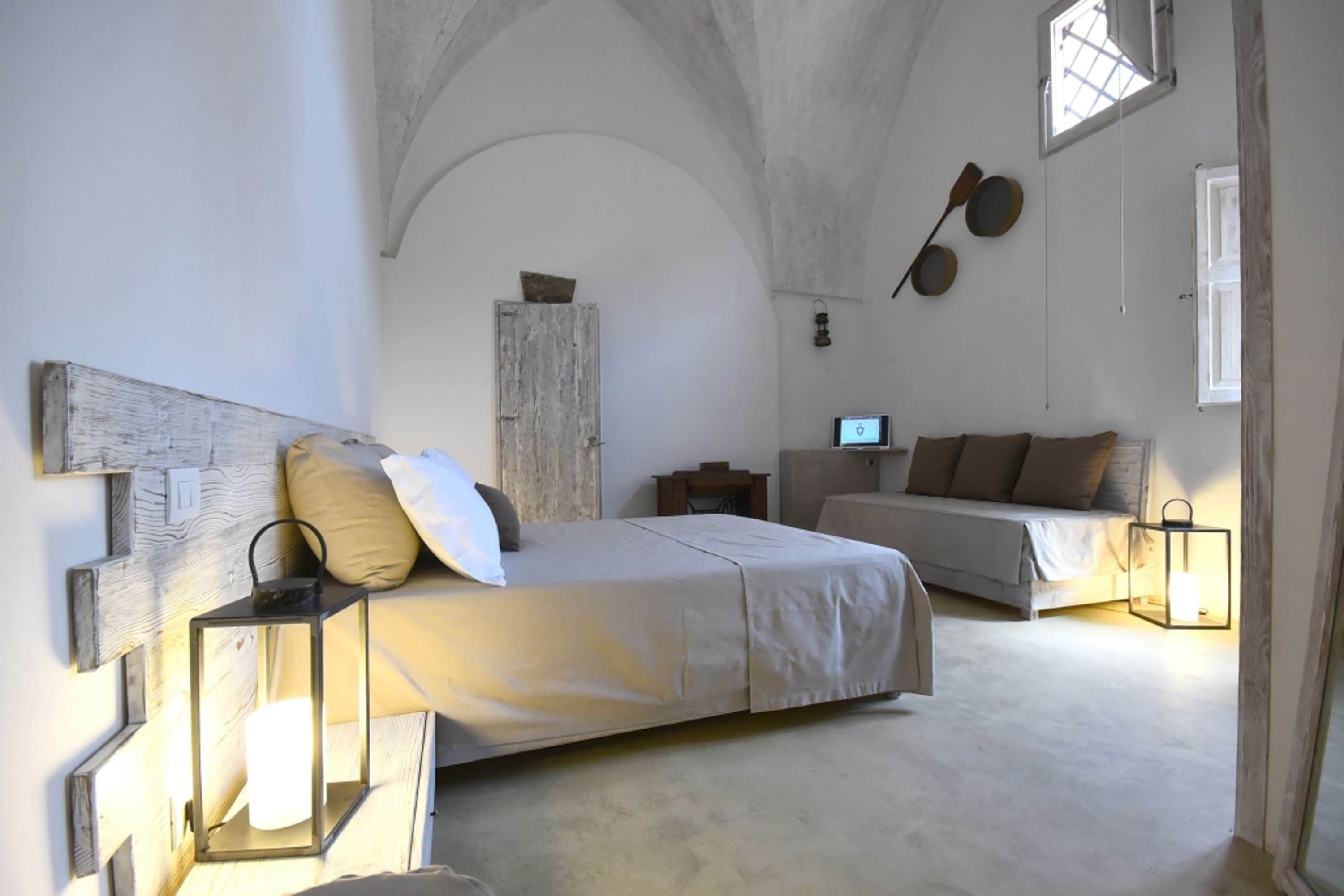 Un dormitorio con una cama grande, un sofá, un cabecero de madera y una mesita.
