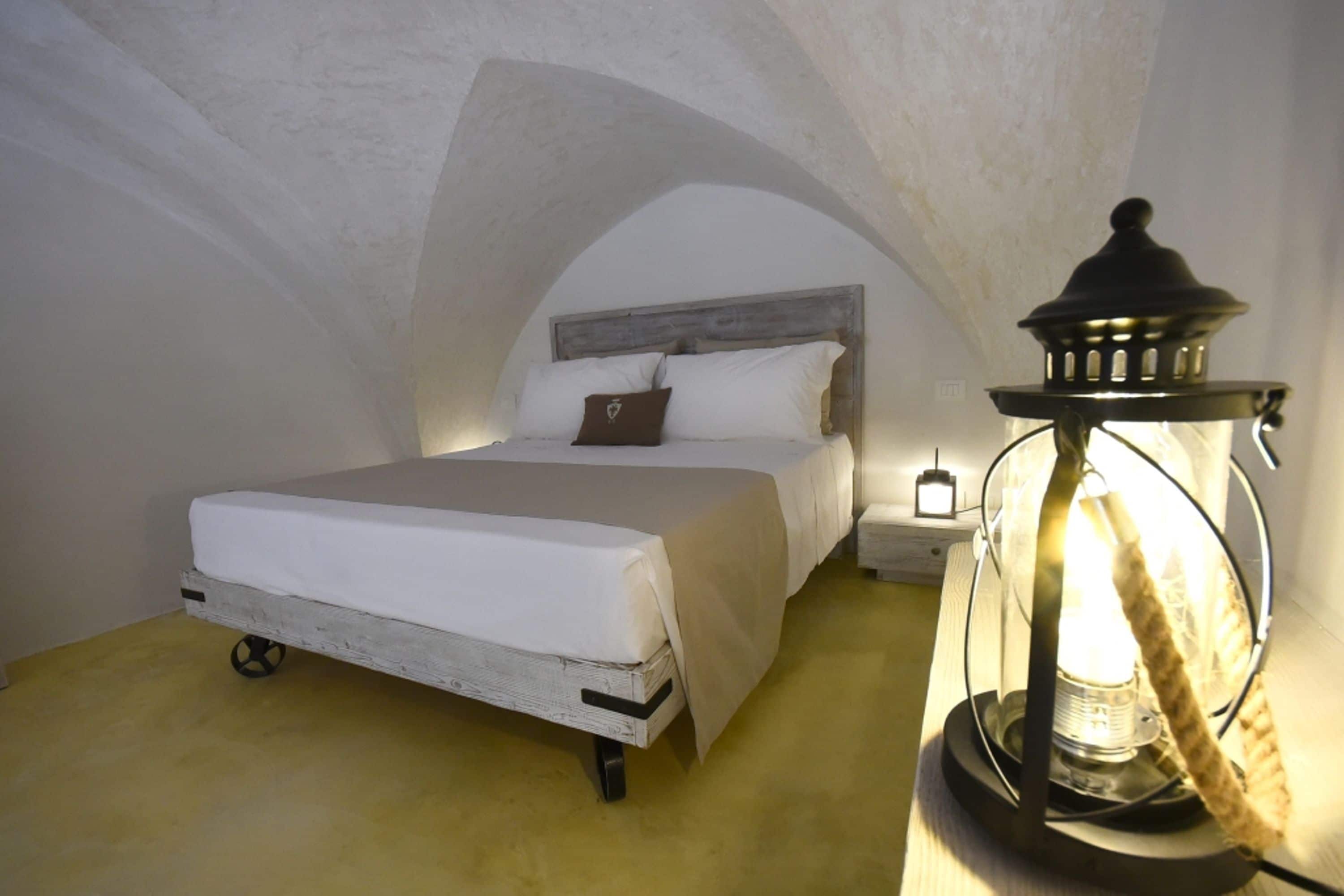 A bedroom with a bed, a nightstand, and a wall-mounted lamp.