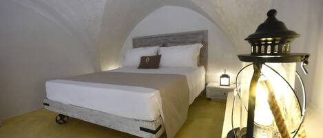 A bedroom with a bed, a nightstand, and a wall-mounted lamp.