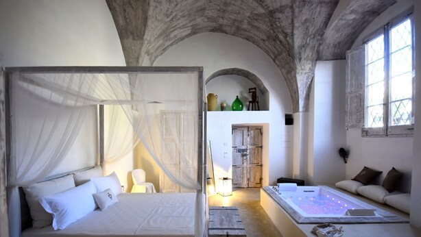 A bedroom with a canopy bed, a massage table, and a sofa. - Palazzo Castriota (Alezio)