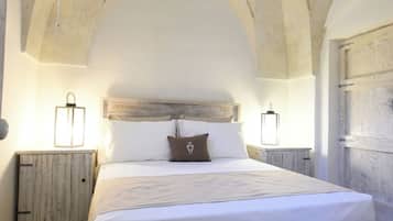 Un dormitorio amplio con una cama grande, cabecera de madera y techo rústico.