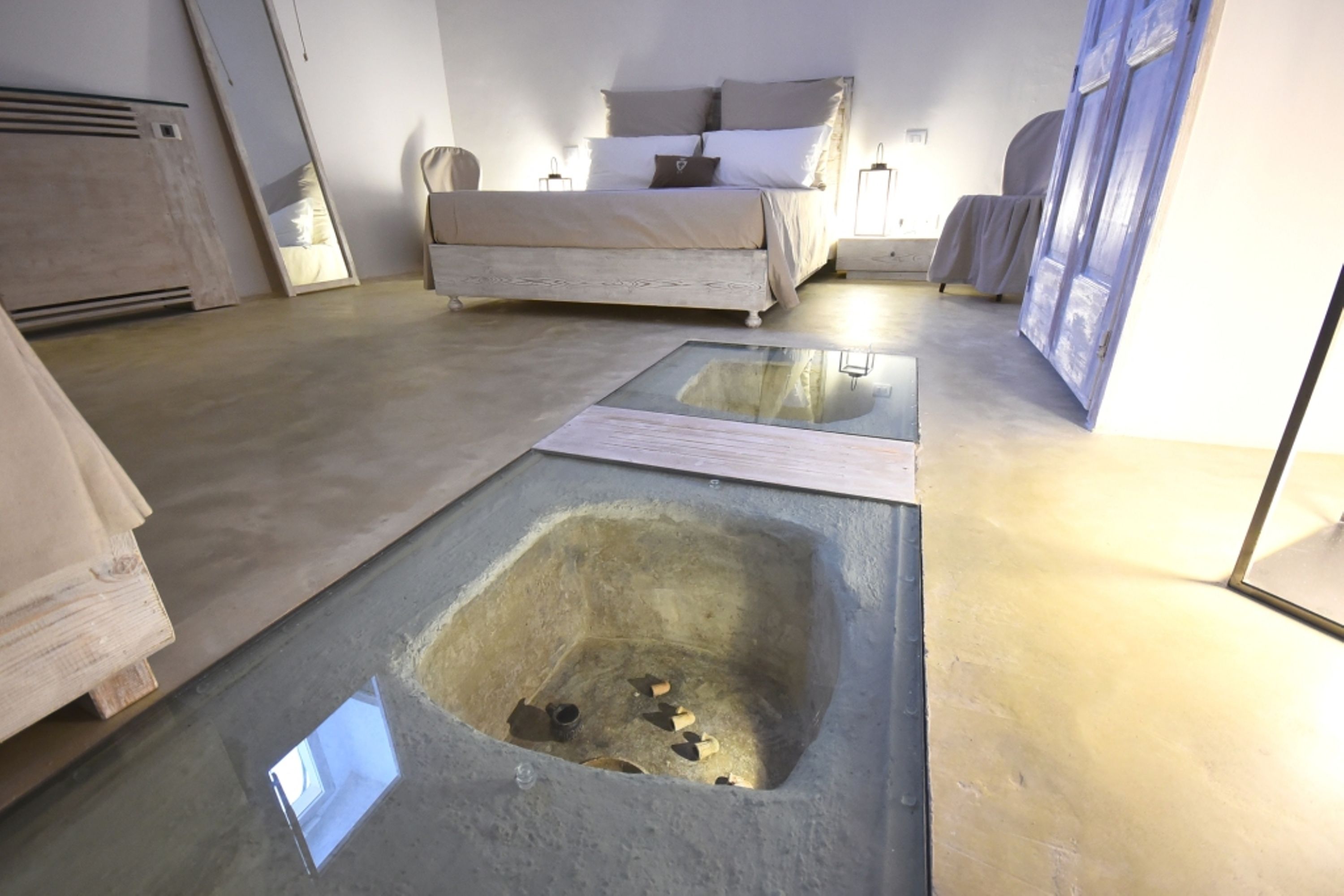 Un dormitorio con cama, mesitas de noche y un panel de suelo de vidrio.