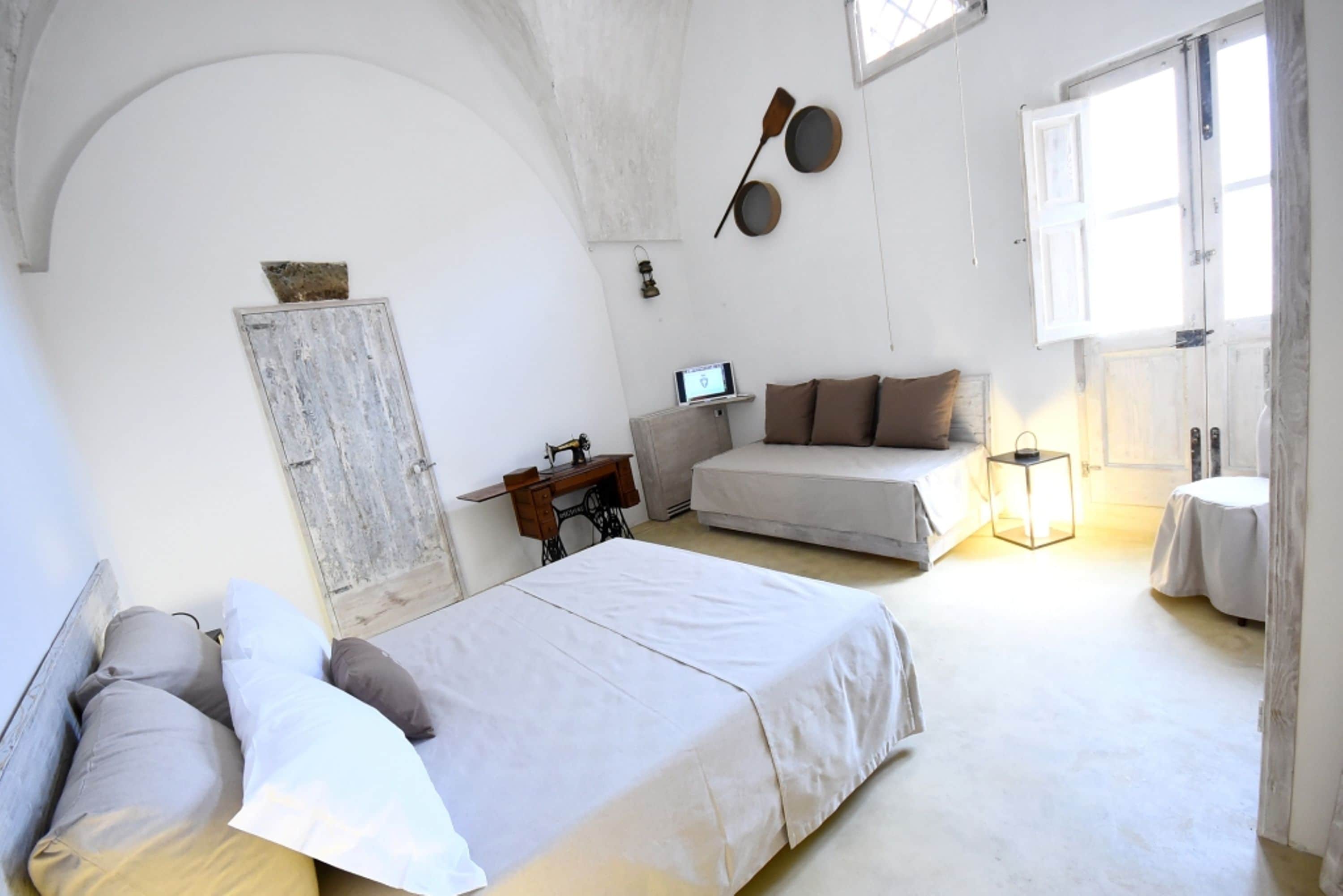 Ein Schlafzimmer mit einem Bett, einem Schreibtisch, einem Stuhl, einem Sofa und einem Fenster.