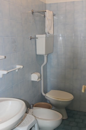 A bathroom with a toilet, sink, and a towel rack. - Hotel Corallo (San Mauro Pascoli)