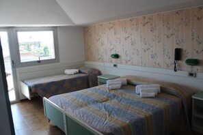 A hotel room with two beds, a window, floral wallpaper, a bedside table, and a nightstand. - Hotel Corallo (San Mauro Pascoli)