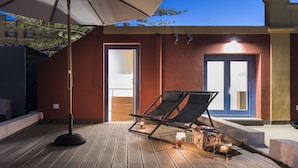 A wooden deck with a lounge chair and an umbrella, a door, and a view of the night sky. - Giardini Mon Plaisir (Trapani)